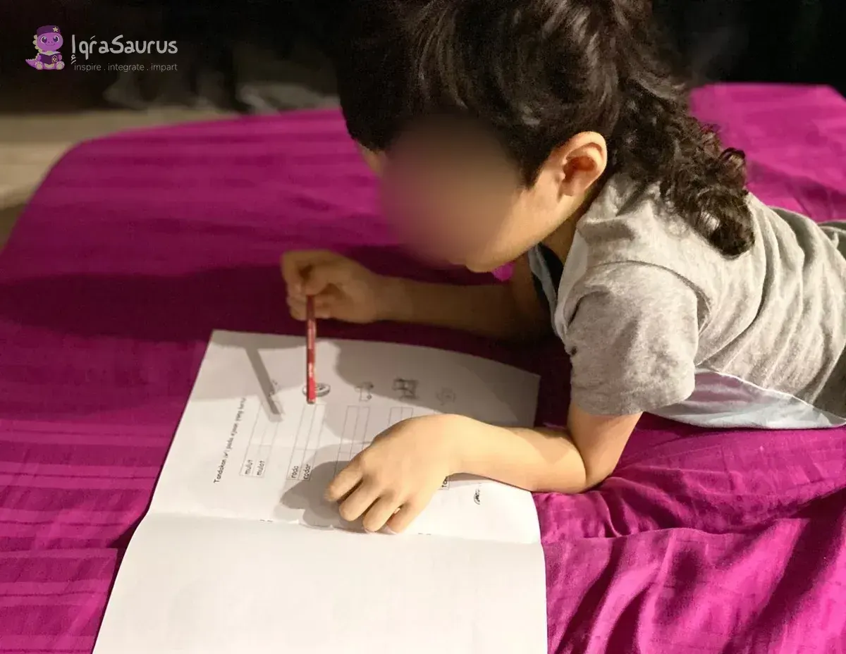 Qoyis lying on a bed working through a practice paper, with the practice-paper booklet and a note in front